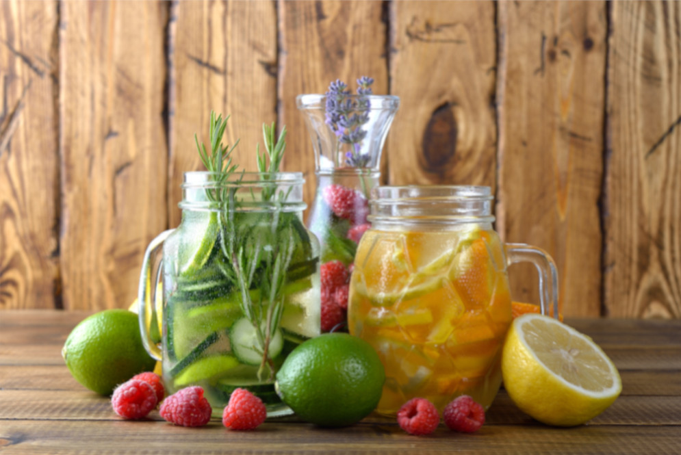 Wasserkrüge, die mit Gurken, Orange, Himbeeren und Kräutern aromatisiert sind.