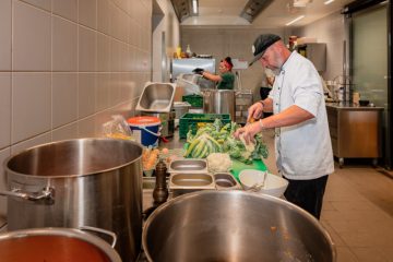 Ein Koch bereitet in einer Großküche Gemüse vor.