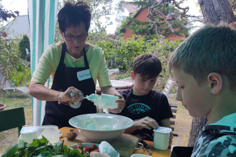 Eine Seniorin und Kinder kochen gemeinsam.